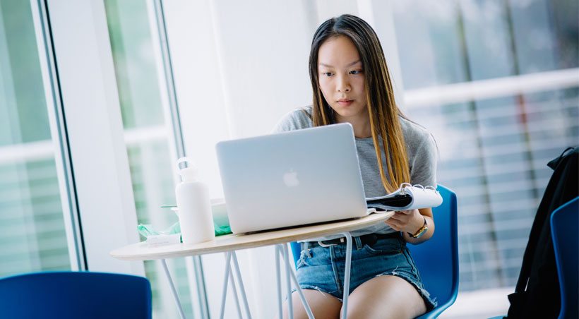 students with laptop sitting at a desk